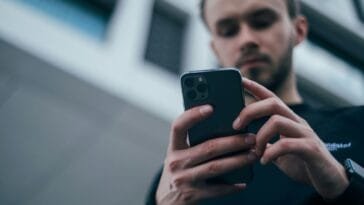 Nuori mies katsoo älypuhelintaan — Ehytin mukaan puolet 18–24-vuotiaista miehistä pitää rahapelaamista trendikkäänä, ja pelaaminen siirtyy yhä voimakkaammin nettiin samalla kun haittojen ehkäisyn rahoitus heikkenee