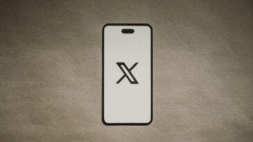 X-logo paperista leikatun puhelimen näytöllä — X on haastanut Duel-kasinon taustayhtiön Immortal Snailin oikeuteen Texasissa ja väittää sen lahjoneen työntekijöitään
